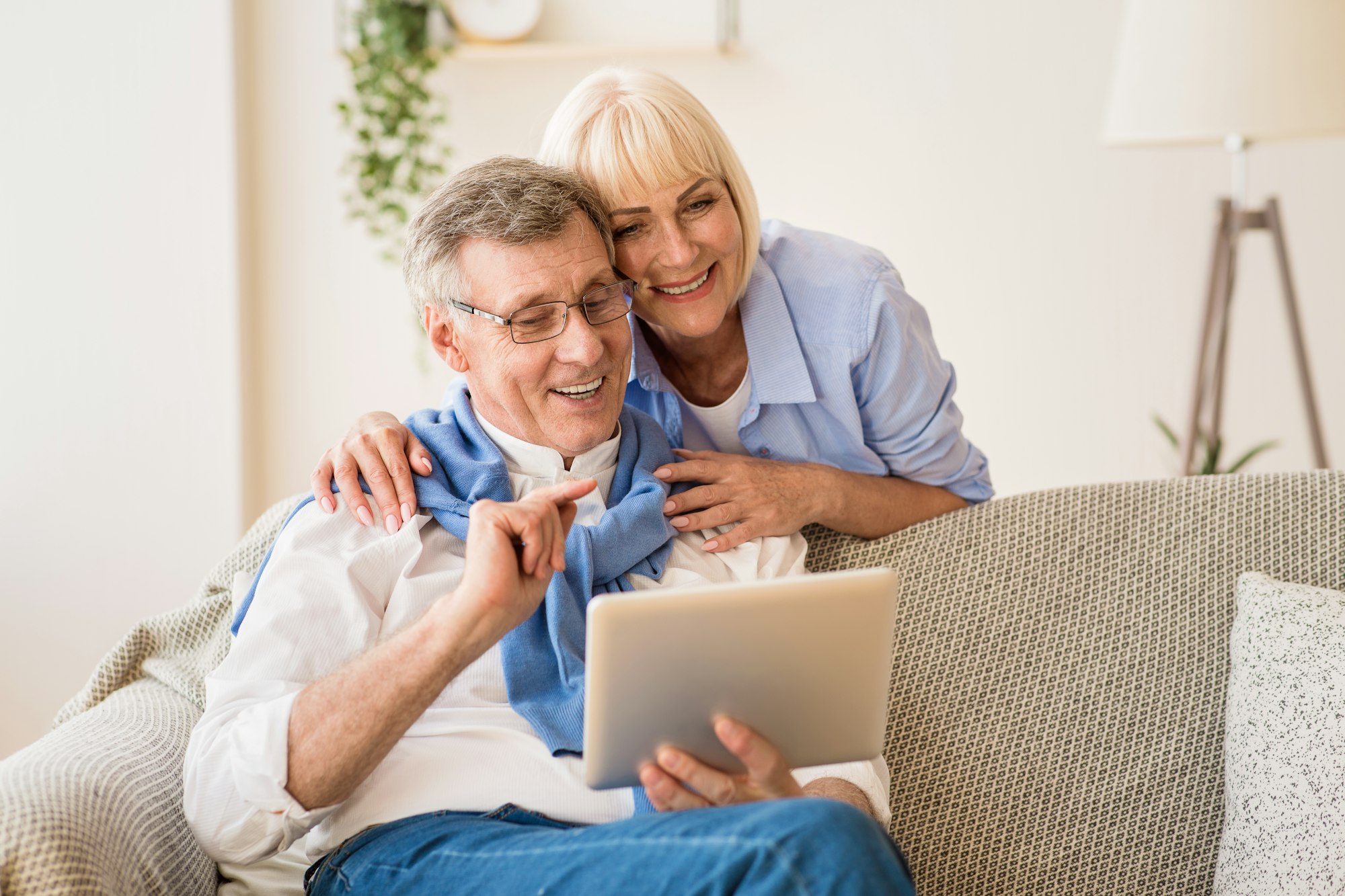 Happy pensioners using tablet, relaxing on rug